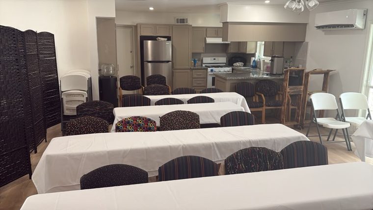 Rows of set tables with the kitchen beyond